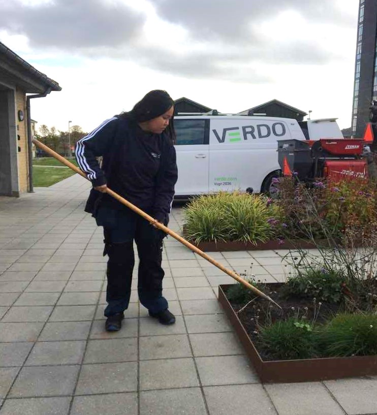 Ung ejendomsfunktionær, der hjælper med at holde områdets beplantning.
